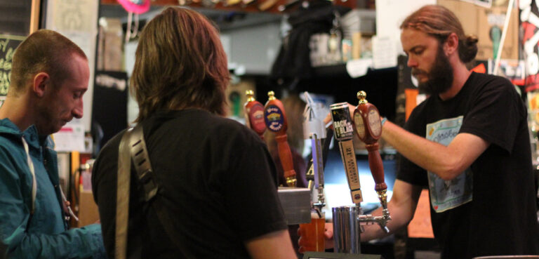A bartender at Beer Revolution in Oakland, CA pours a couple a pint.