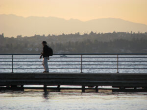 A photographer walks along a dock at dusk by the water in Renton, WA.