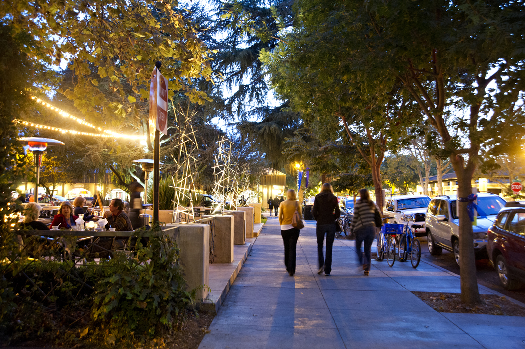 Three ladies walk past a restaurant near twilight in Davis, CA