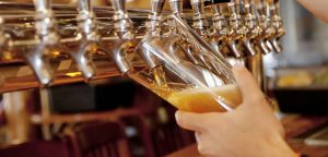 beer glass being filled from a row of shiny taps.