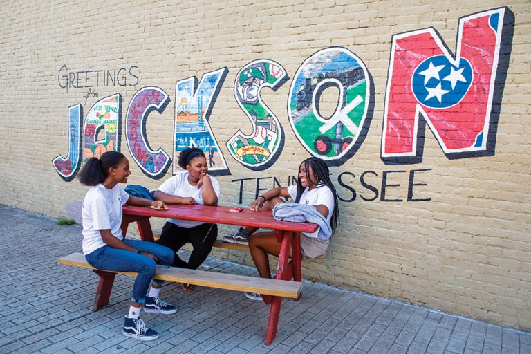 Youth leadership program members Lisa Nnaji, left, Serenity Williams and Amber Calhoun talk while sitting under the Jackson mural in downtown Jackson, TN.