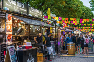 Line of food vendors with people outside at a festival