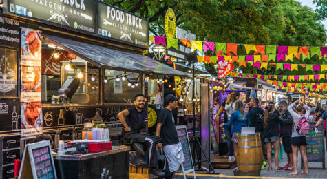 Line of food vendors with people outside at a festival