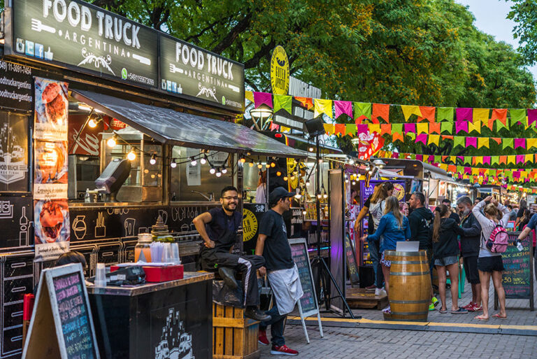 Line of food vendors with people outside at a festival