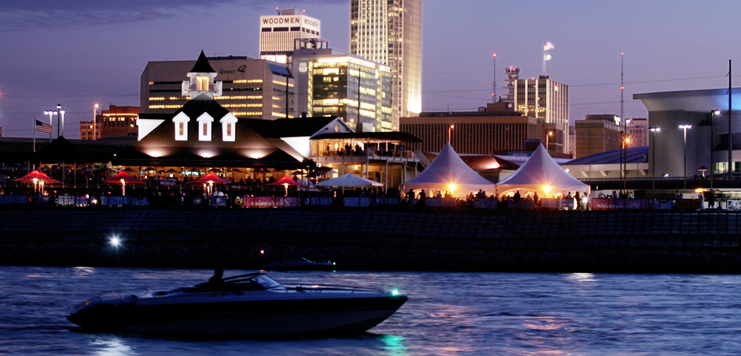 View of the Omaha downtown skyline at night with a boat in the water.