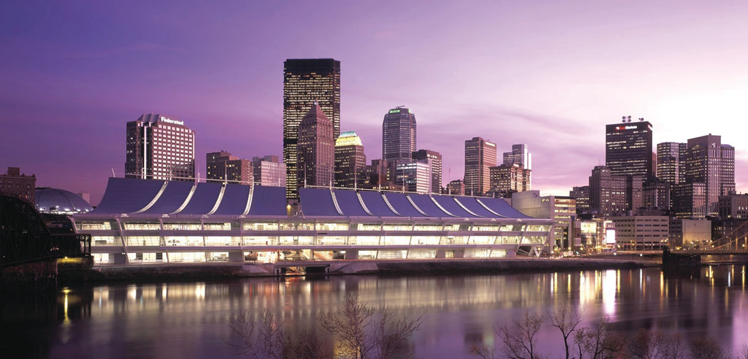 The illuminated Convention Center reflects in the water of a river that flows around downtown Pittsburgh, PA