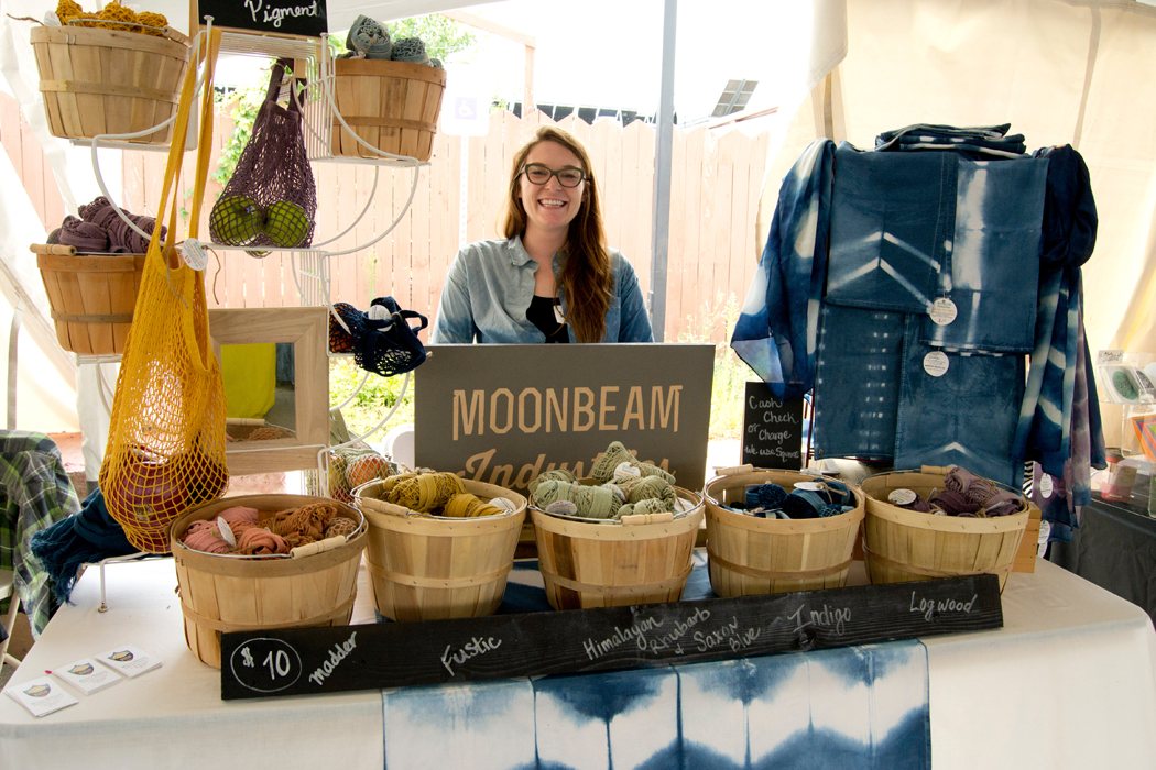 A young entrepreneur behind the counter of a bag store in a tent.