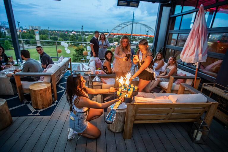 Group of girls take shots out of a guitar at Hampton Social in downtown Nashville