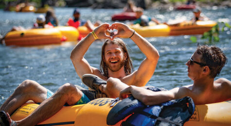man showing heart sign on river tube