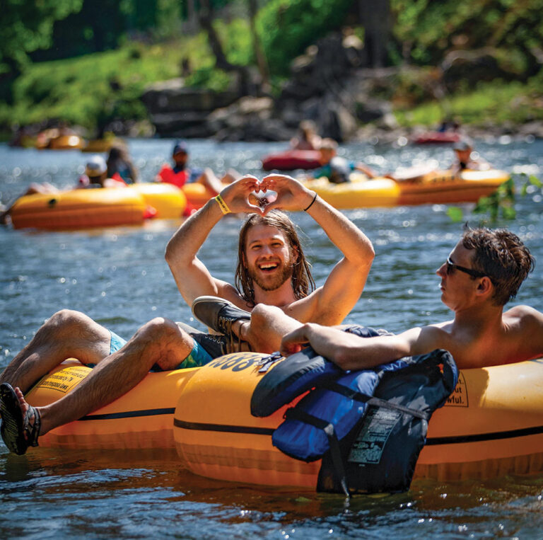 man showing heart sign on river tube