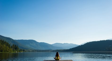 Female doing some soul searching and meditating doing sukhasana or Easy Pose during a yoga working at a pristine mountain lake