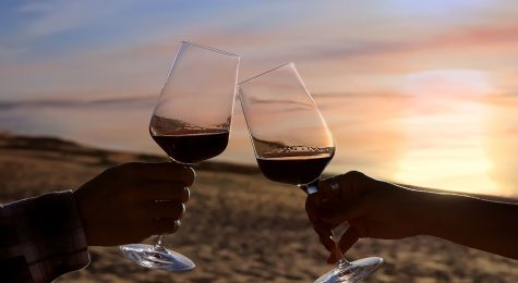 Selective focus of couple hands which Couple drinking wine in sea restaurant on the beach background