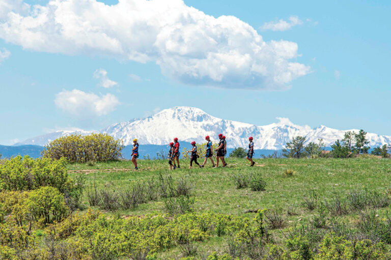 Castle Rock, CO: People walking on a zip line tour with mountains in the background.