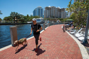 Man running with his dog along the New River at Riverwalk Fort Lauderdale in downtown Fort Lauderdale, Florida.