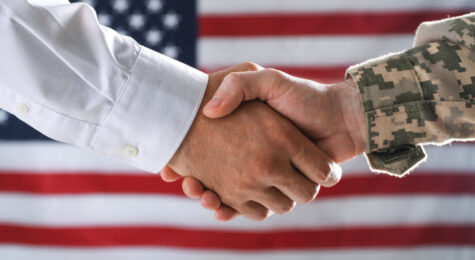 Soldier and businessman shaking hands against flag of USA, closeup