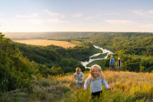 A group of children run through a field in North Dakota.