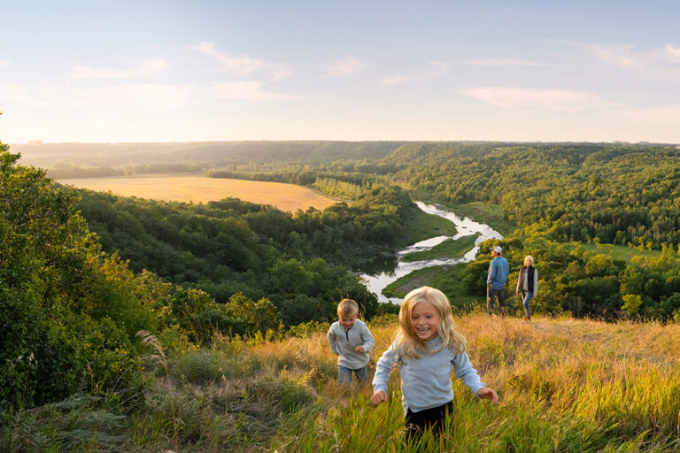 A group of children run through a field in North Dakota.