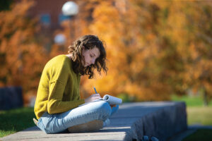 Student writes in a notebook on the University of Cincinnati campus in the Northern Kentucky region.