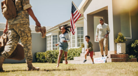 Military mom receiving a warm welcome from her husband and kids. American servicewoman reuniting with her family after serving in the army. Female soldier returning home from deployment.
