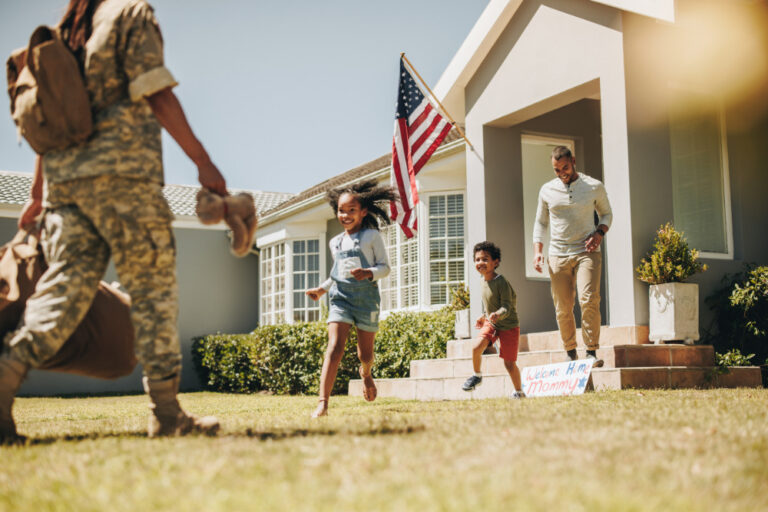 Military mom receiving a warm welcome from her husband and kids. American servicewoman reuniting with her family after serving in the army. Female soldier returning home from deployment.