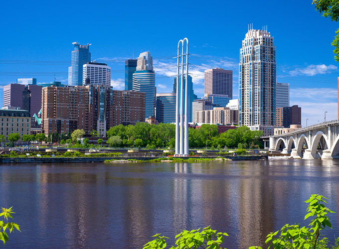 The Mississippi River flows southward by the Minneapolis, MN, skyline. Amenities like a thriving arts and culture scene and cosmopolitan restaurants make Minneapolis one of the best places to live in the U.S.