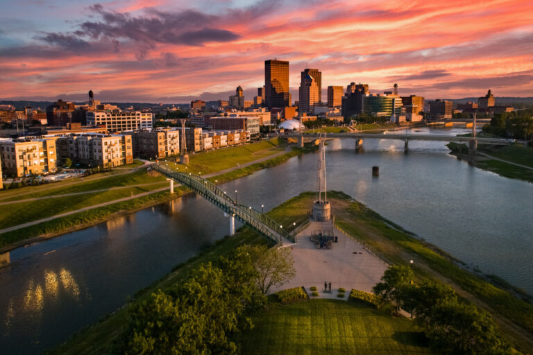 An aerial drone view over a park looking towards downtown Dayton, Ohio at sunset at the confluence of the Great Miami and Mad Rivers.