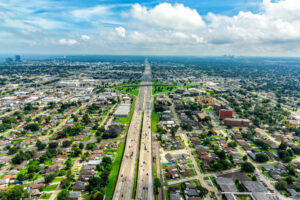 Aerial view of Interstate 10 bisecting Metairie, Louisiana, with New Orleans in the distance.