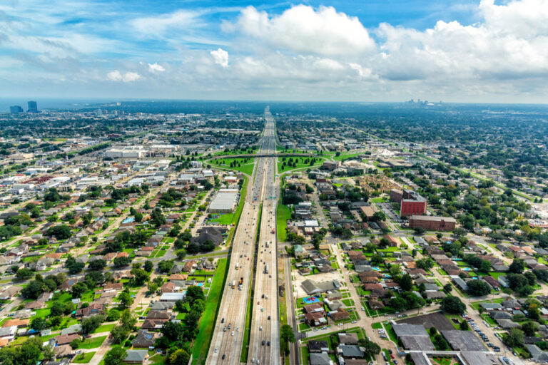Aerial view of Interstate 10 bisecting Metairie, Louisiana, with New Orleans in the distance.